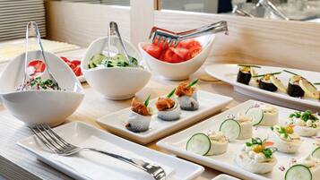 Una mesa de buffet con diversos platos, como sushi, ensaladas y aperitivos.