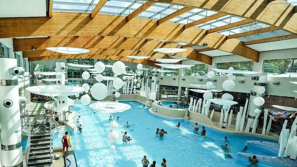 An indoor swimming pool with multiple lanes and a wooden ceiling structure. - Aqua House (Sopot)