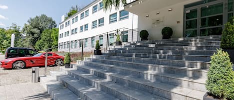 Un bâtiment moderne avec un escalier en pierre menant à une entrée constituée d’une porte en verre.