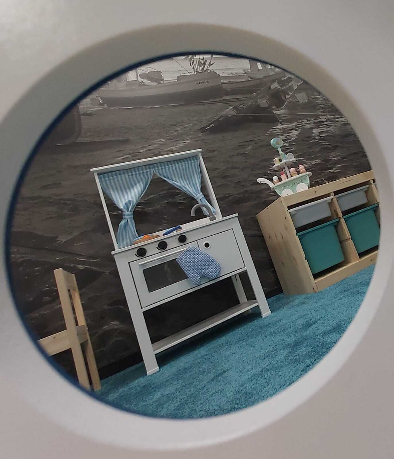 A circular view of a room with a small kitchenette, a window with curtains, and a blue carpet.