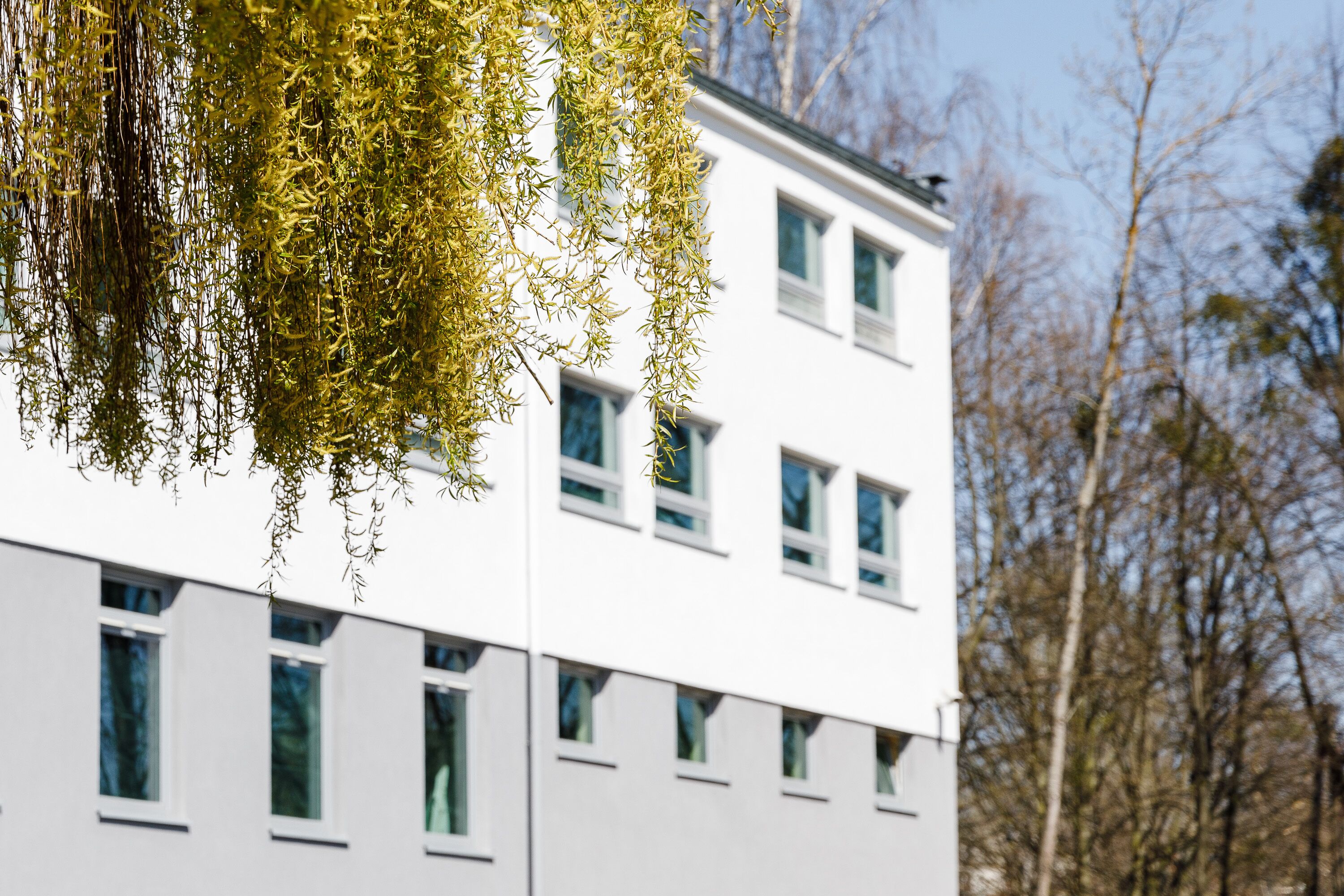 A multi-story building with a white facade and multiple windows.