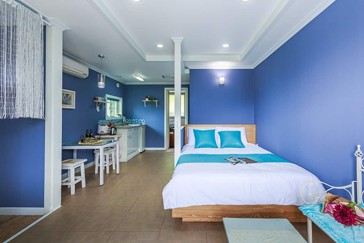 A bedroom with a bed, a desk, and a chair.