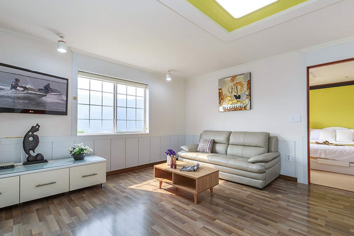 A modern living room with a sofa, coffee table, and a TV mounted on the wall.