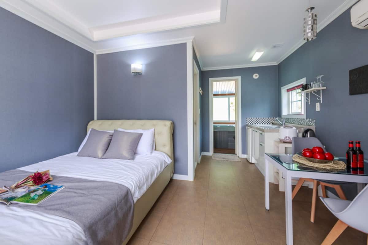A bedroom with a bed, bedside table, and a view of the bathroom.