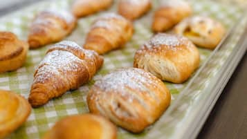 Eine Auswahl an Gebäck, darunter Croissants und Blätterteigtaschen, bestäubt mit Puderzucker.