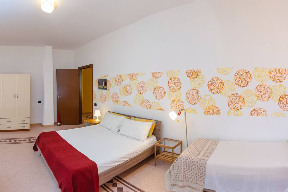 A hotel room with two beds, a sofa, a small table, and a wardrobe.