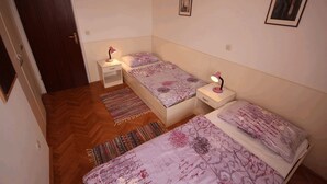 Un dormitorio pequeño y bien iluminado con dos camas individuales, piso de madera y una puerta.
