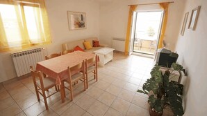Una sala de estar con una mesa de comedor, sillas, un sofá, un radiador y una planta en maceta.