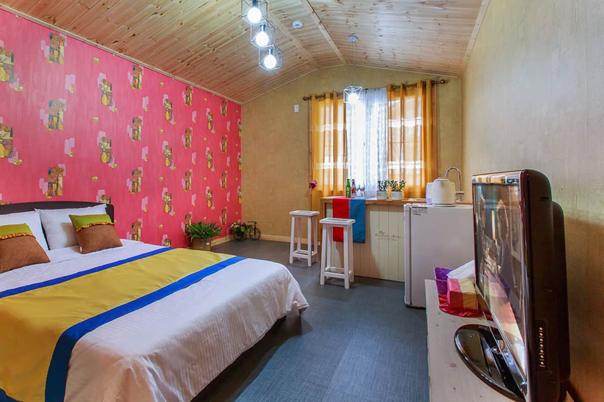 Ein Zimmer mit einem Bett, einer kleinen Küchenzeile und einem Fernseher.