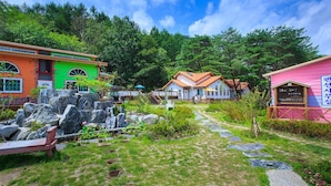 A colorful building with a stone pathway leading to a wooden deck. - Lake and Pine Spa Pension (Pocheon)
