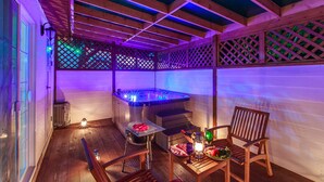 A wooden deck with a hot tub, a grill, and a dining table with chairs. - Lake and Pine Spa Pension (Pocheon)
