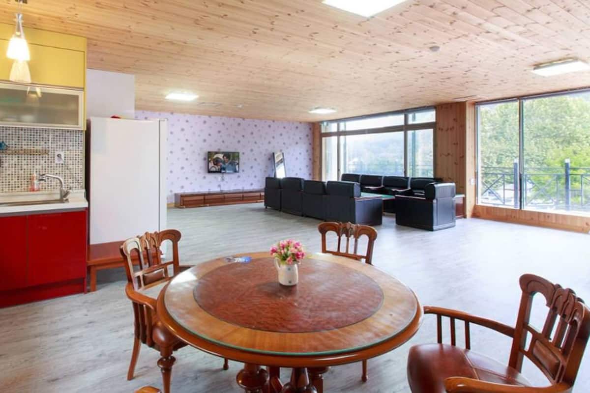 Eine moderne Küche mit roten Schränken, einem Holzes Esstisch mit Stühlen und einem großen Fenster mit Blick auf einen Balkon.