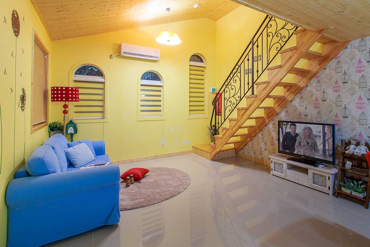 Ein Wohnzimmer mit einem blauen Sofa, einem roten Sessel, einem Fernseher und einer Treppe.