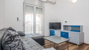 Una sala moderna con un sofá gris, una mesita y un televisor.