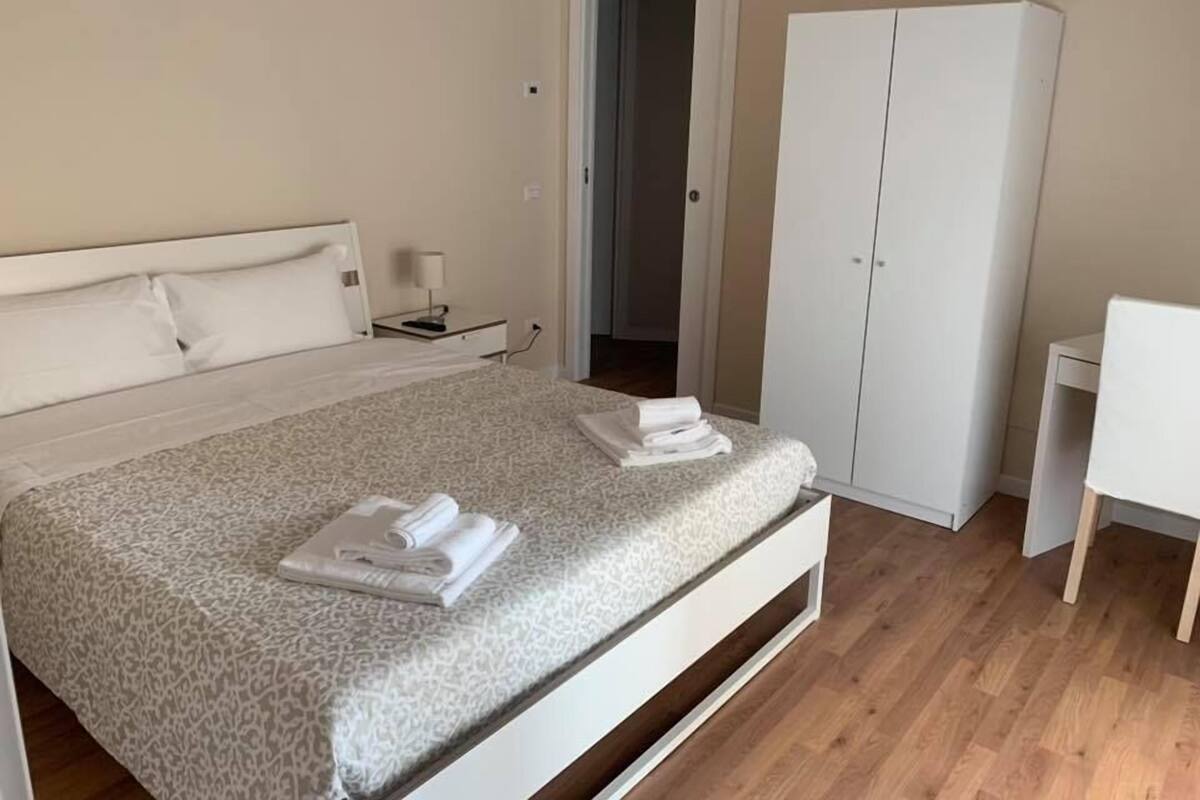 A bedroom with a bed, a nightstand, a wardrobe, and a chair.