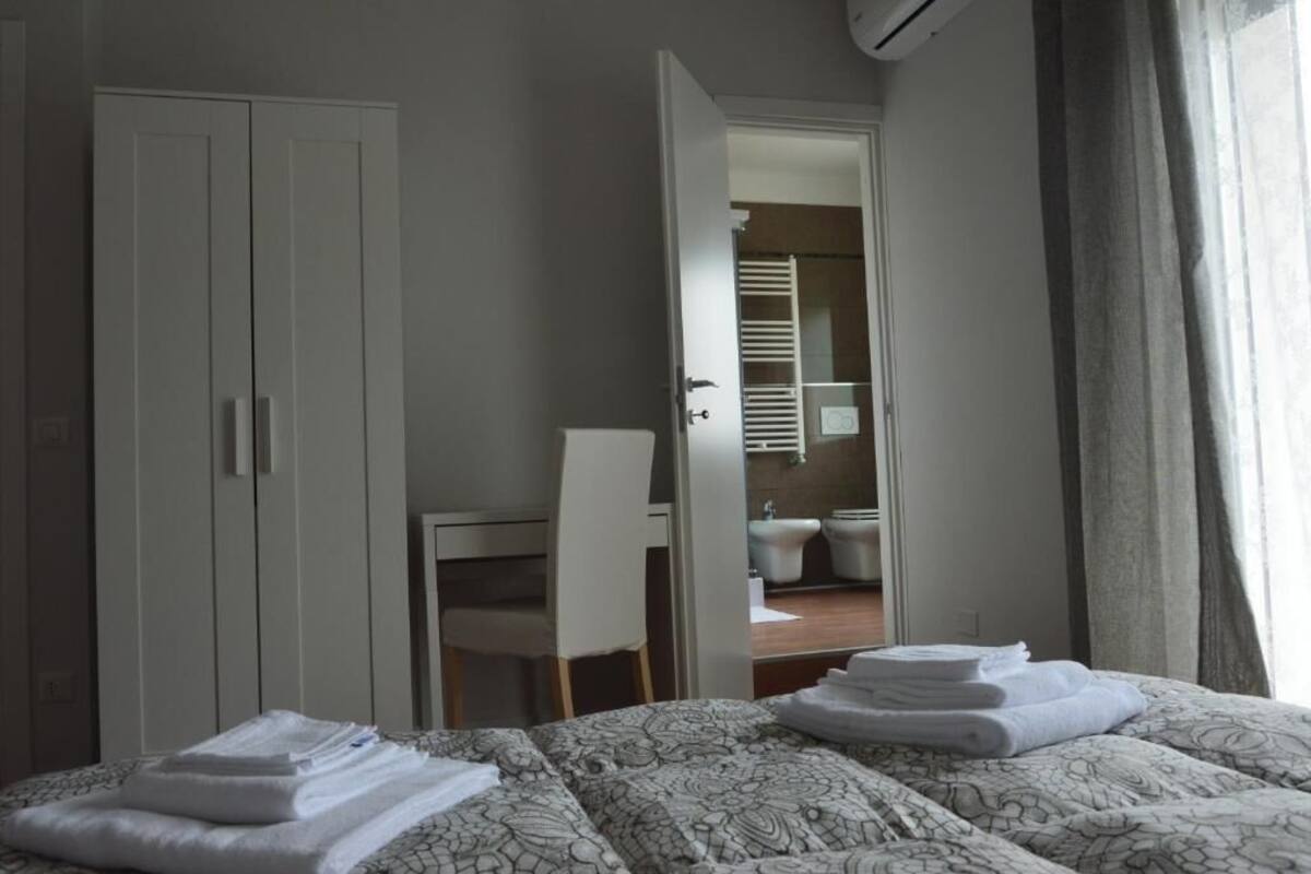 A hotel room with a bed, a desk, a chair, and a bathroom visible through an open door.
