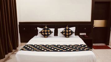 A neatly made bed with a checkered bedspread and two decorative pillows, a dark headboard, and a nightstand with a lamp.