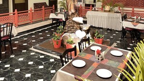 Un comedor de varios niveles con mesas dispuestas para comensales, una fuente decorativa y una estatua.