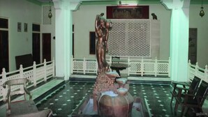 Una habitación con una estatua, una cerca blanca y un piso estampado.