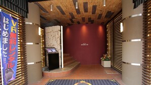 A hotel entrance with a wooden ceiling, a red wall, and a VIP check-in area. - Hotel GOMAX - Adults Only (Yokohama)