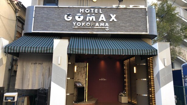 The exterior of Hotel Gomax Yoko-Hama with a modern design, including a striped awning and a signboard. - Hotel GOMAX - Adults Only (Yokohama)
