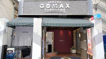 The entrance to Hotel Gomax Yoko-hama with a striped awning, a 'Staff Only' sign, and a 'MAX GO' sign.