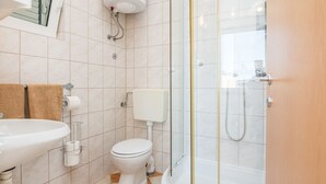 A bathroom with a sink, toilet, and glass-enclosed shower. - Apartments Bojana (Vir)