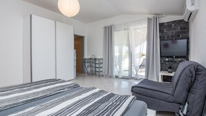 A modern bedroom with a bed, a sofa, a TV, and a dining area. - Apartments Bojana (Vir)