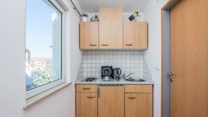 A compact kitchen with wooden cabinets, a coffee maker, and a kettle on the countertop. - Apartments Bojana (Vir)