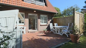 A house with a brick patio, white outdoor furniture, and a wooden fence. - Sylt at home, Germany (Sylt-Ost)
