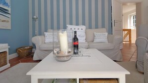 A living room with a white sofa, a glass table with a candle, and a bottle of wine. - Sylt at home, Germany (Sylt-Ost)