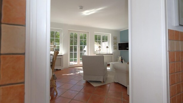 A spacious room with large windows, a white chair, and a radiator. - Sylt at home, Germany (Sylt-Ost)