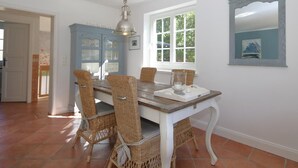 A dining area with a white table, wicker chairs, and a blue cabinet. - Sylt at home, Germany (Sylt-Ost)
