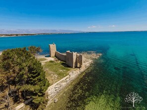 An aerial view of a coastal historical site with ruins and clear turquoise waters. - Apartments Puskaric (Vir)