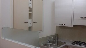 Une cuisine de taille réduite, équipée d’un évier, d’une cuisinière et de placards hauts.