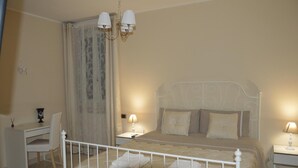 A bedroom with a bed, bedside tables, a desk, and a chair. - La Colomba B&B (Altamura)