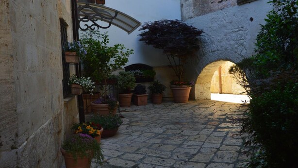 A narrow cobblestone alley with potted plants and a small archway. - La Colomba B&B (Altamura)