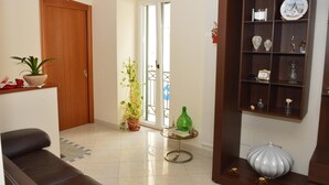A living room with a sofa, a coffee table, a bookshelf, and a door leading to a balcony. - La Colomba B&B (Altamura)