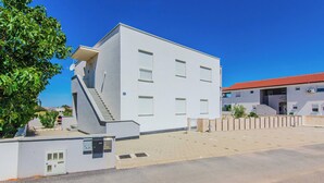A modern building with a flat roof, multiple windows, and a staircase leading to the entrance. - Apartment Andreja (Vir)