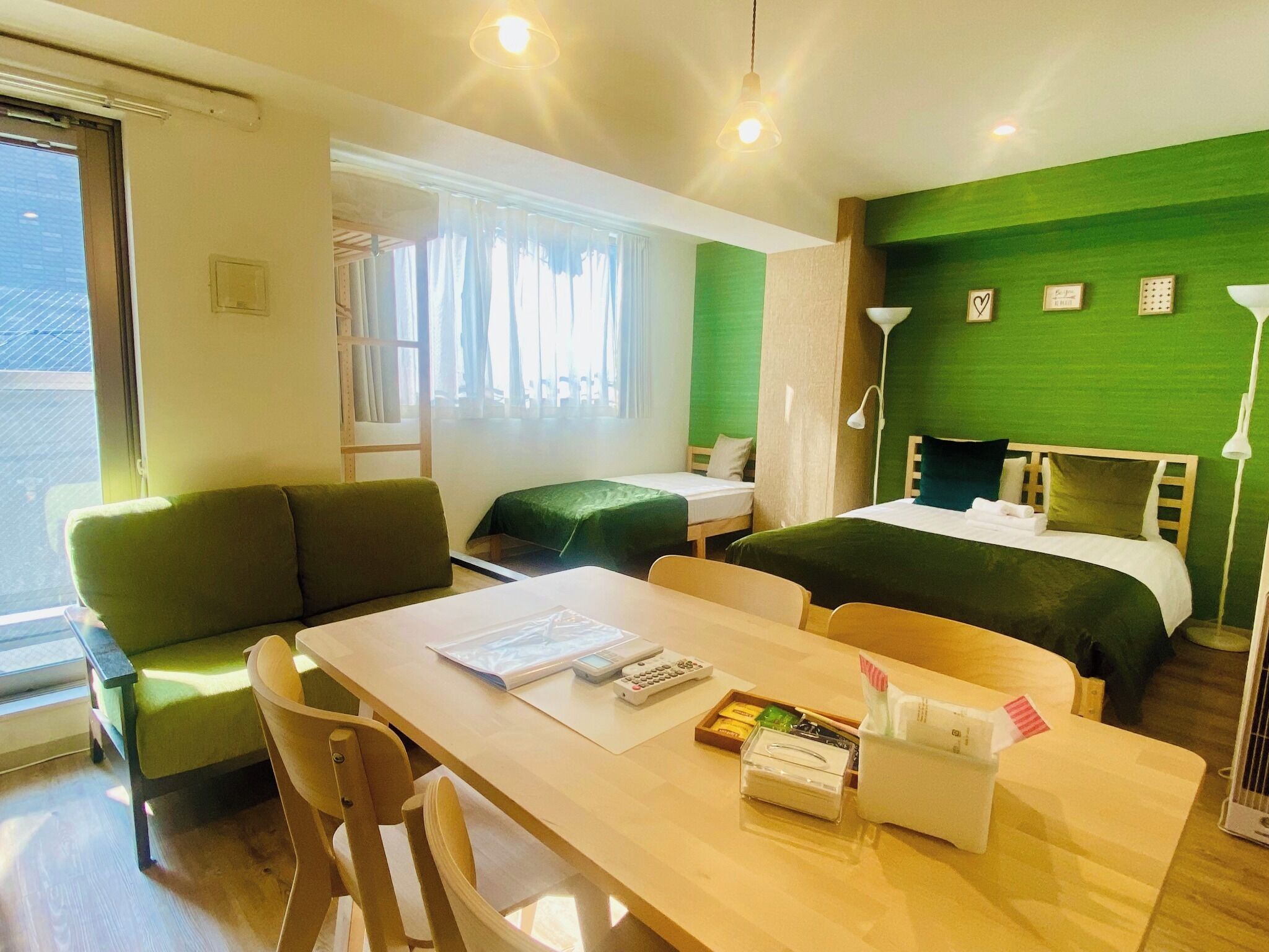 A hotel room with a bed, a desk with a chair, a sofa, and a window.