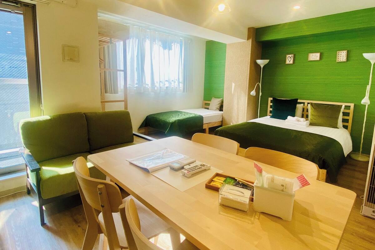 A hotel room with a bed, a desk with a chair, a sofa, and a window.