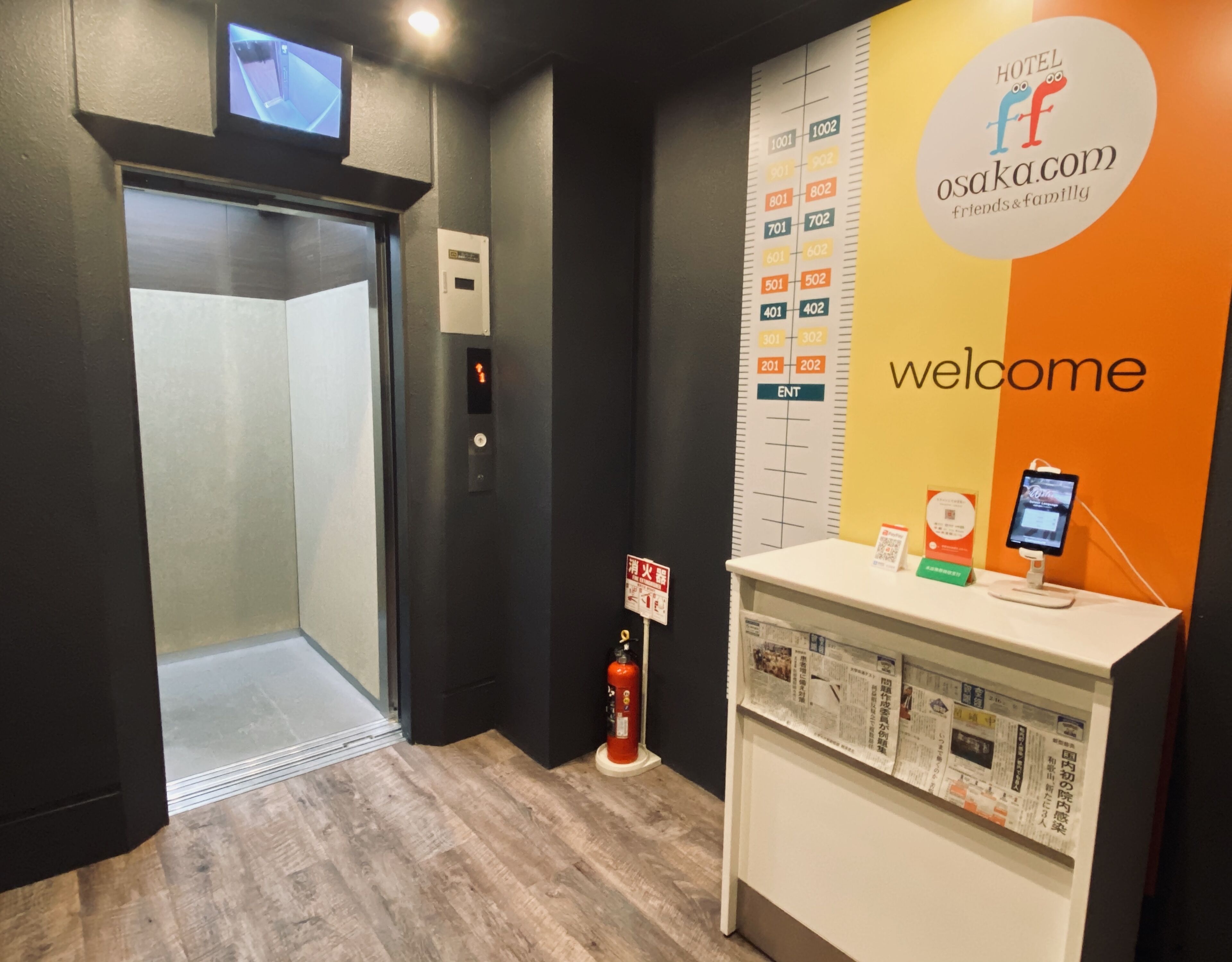 A hotel reception area with a digital display, a fire extinguisher, and a welcome sign.