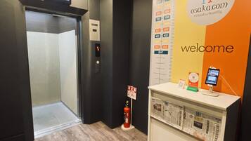 A hotel reception area with a digital display, a fire extinguisher, and a welcome sign.