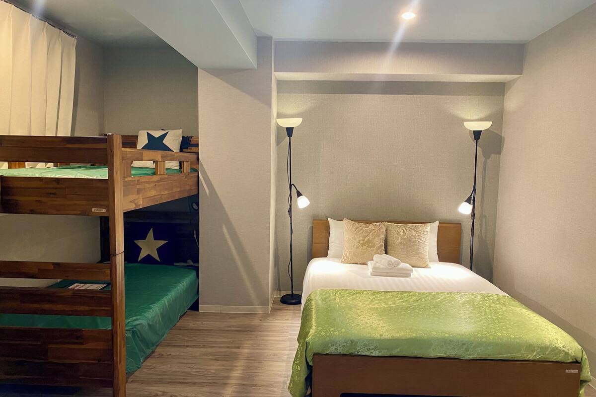 A room with a bunk bed, a single bed, and two standing lamps.