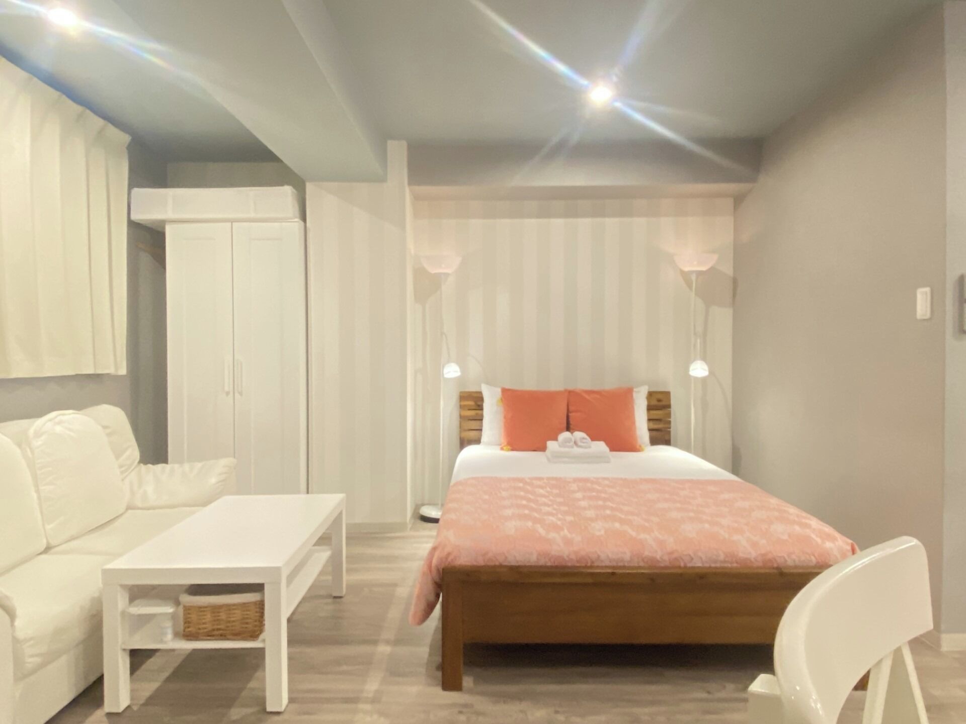 A bedroom with a bed, a bedside table, a chair, a wardrobe, and a window with curtains.