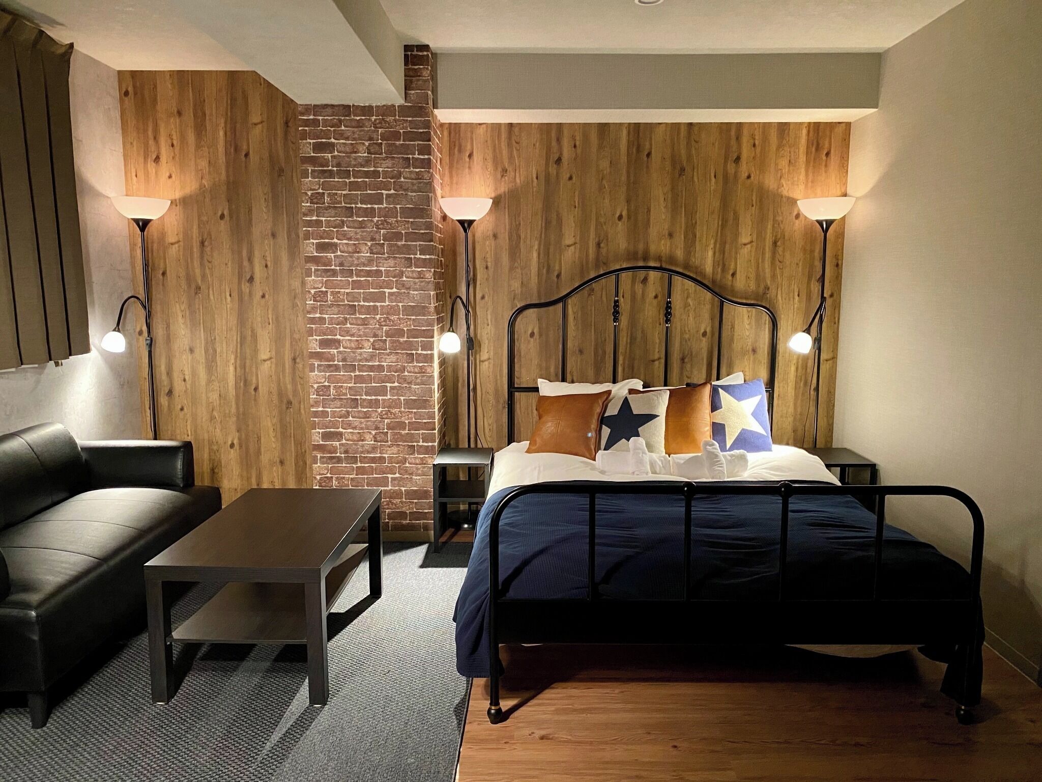A bedroom with a bed, a nightstand, a lamp, a chair, and a small table.