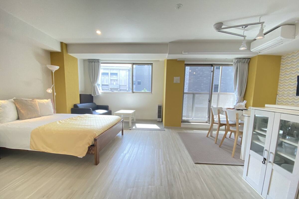A hotel room with a bed, a desk, a chair, and a cabinet.