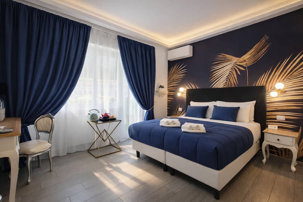 A modern hotel room with a large bed, a desk, and a chair.