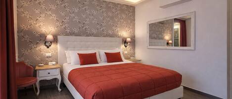 Un dormitorio moderno con una cama grande, dos mesitas de noche, un revistero, una silla roja y un espejo en la pared.