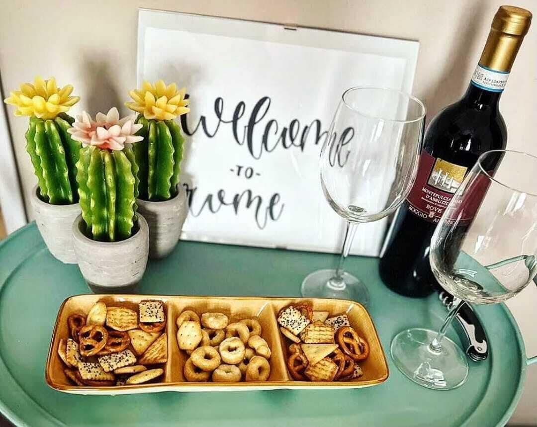 Une table avec une pancarte sur laquelle on peut lire « Bienvenue chez vous », une bouteille de vin et un plateau de collations.